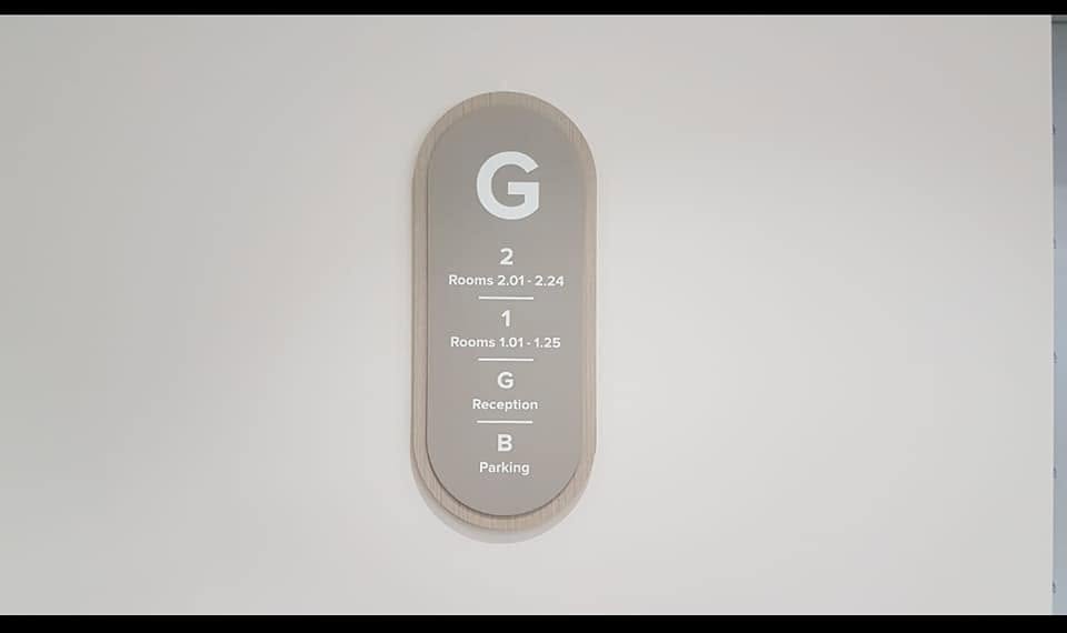 Floor directory sign listing levels and rooms on a timber backing