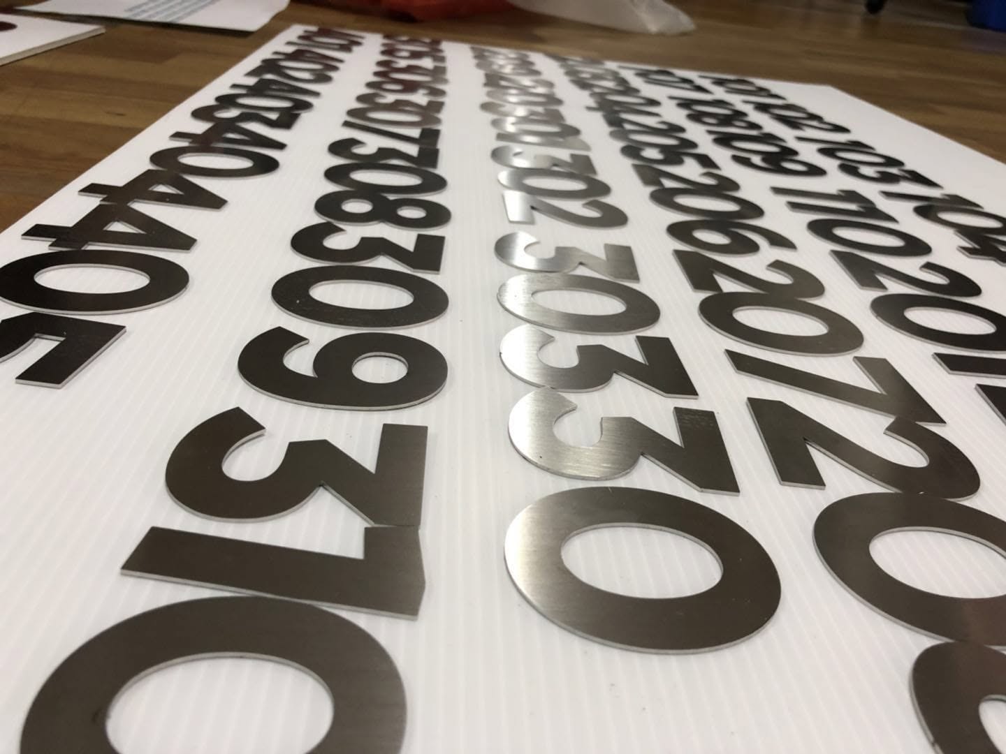 Stainless steel number cutouts laid out ready for install