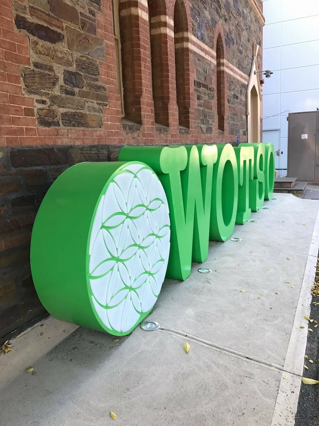 Fabricated 3D letters ready for install against a brick facade