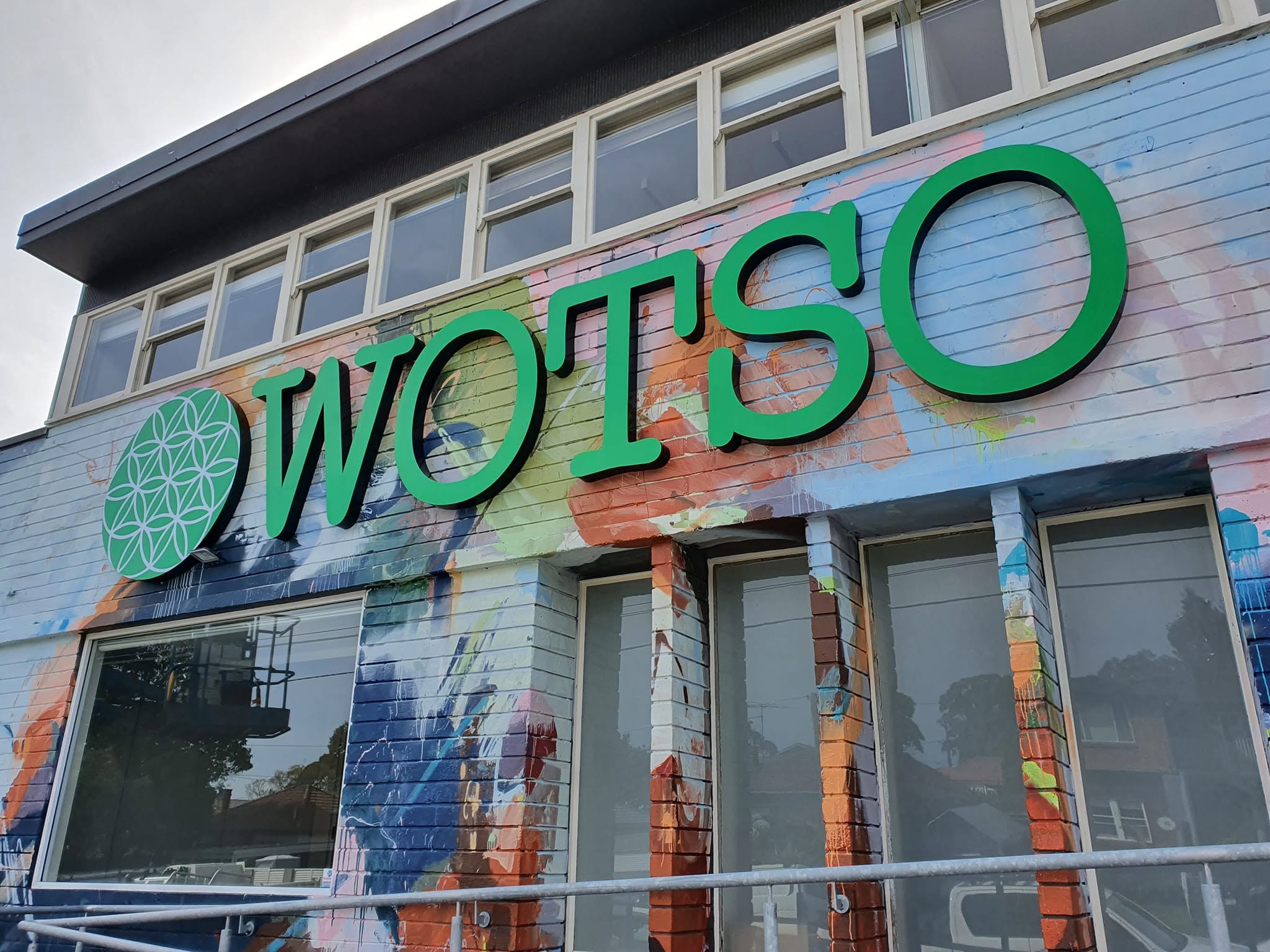 Fabricated WOTSO letters and logo disc across a painted mural facade